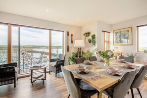 A dining area with a view of a marina, a table set with plates and cutlery, and a chair with a cushion. - 3 Bed in Amble (oc-s43277) (Amble)