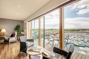 A spacious balcony with a view of a marina, furnished with chairs and tables, and a potted plant. - 3 Bed in Amble (oc-s43277) (Amble)