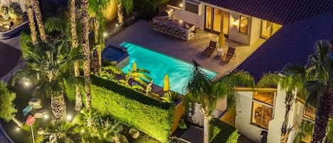 Ein Wohnhaus mit Schwimmbad, Sitzgelegenheiten im Freien und gepflegter Gartenanlage.