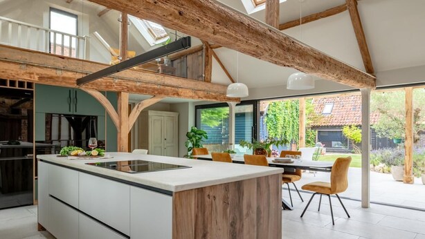 A modern kitchen with a central island, wooden beams, and a dining area with outdoor seating. - 3 Bed in Ditchingham (oc-s42751) (Ditchingham)