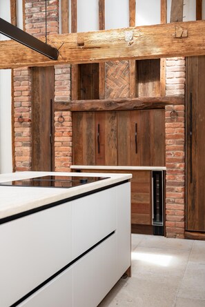 A modern kitchen with a white countertop, wooden beams, and brick walls. - 3 Bed in Ditchingham (oc-s42751) (Ditchingham)