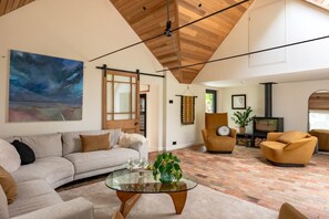 A living room with a sofa, armchairs, a glass coffee table, and a fireplace. - 3 Bed in Ditchingham (oc-s42751) (Ditchingham)