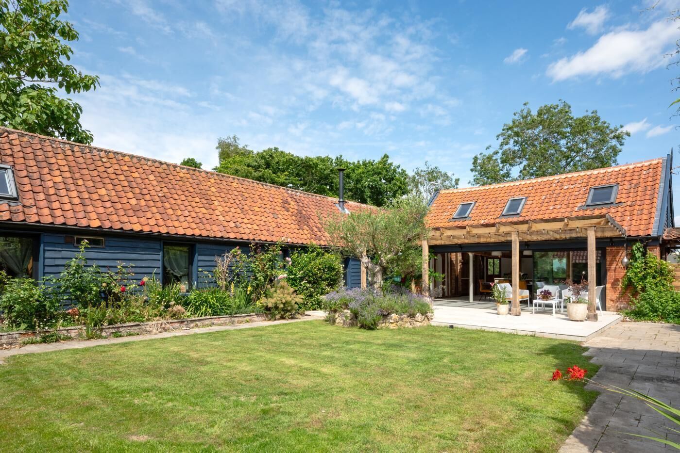 Un bâtiment à deux étages, doté d’un toit recouvert de tuiles, d’un patio abrité et d’une pelouse bien entretenue.