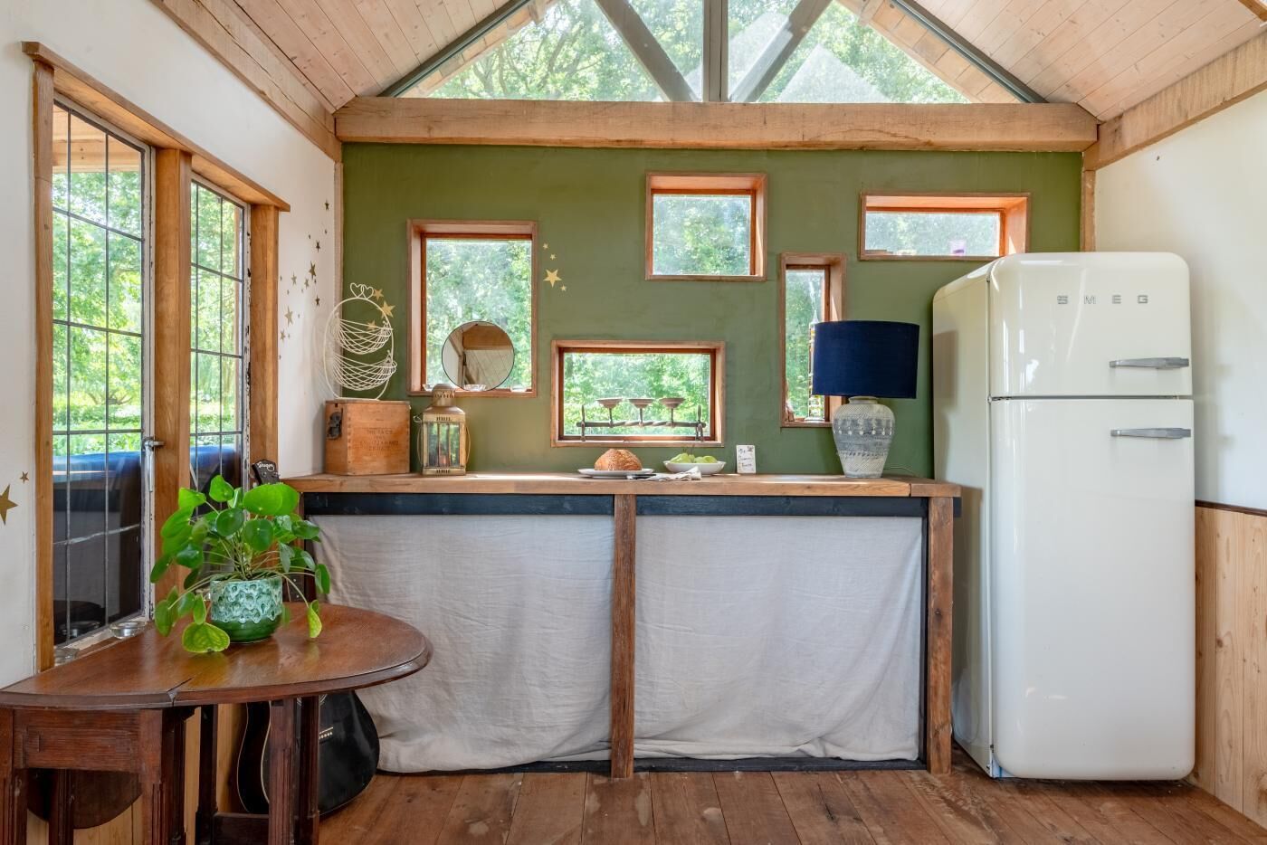 Une cuisine compacte avec un comptoir en bois, un réfrigérateur et une table à manger agrémentée d’une plante en pot.