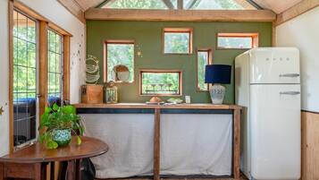 Une cuisine compacte avec un comptoir en bois, un réfrigérateur et une table à manger agrémentée d’une plante en pot.