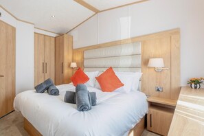 A hotel room with a large bed, wooden wardrobe, bedside lamps, and a small table with a vase of flowers. - 2 Bed in Cockermouth (oc-c43275) (Cockermouth)