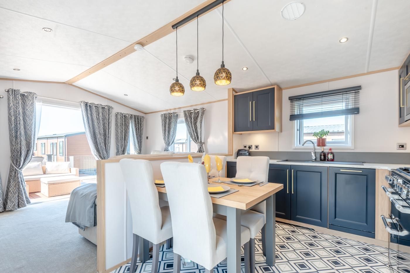 A modern kitchen with dark cabinets, a wooden dining table, and pendant lighting.