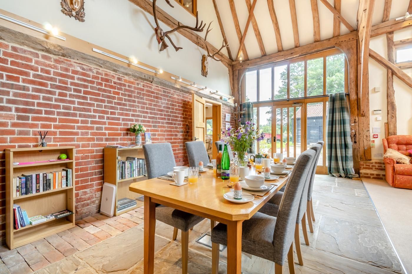 A dining area with a brick wall, wooden beams, and a large window.