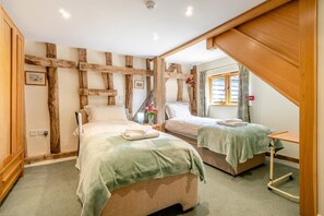 A bedroom with two beds, wooden beams on the walls, a small table, and a window with curtains. - 3 Bed in Chediston (oc-b43313) (Chediston)