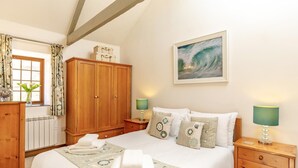 A bedroom with a bed, bedside tables, a wardrobe, a window with curtains, and a painting on the wall. - 2 Bed in Hayle (oc-l42842) (Saint Erth Praze)
