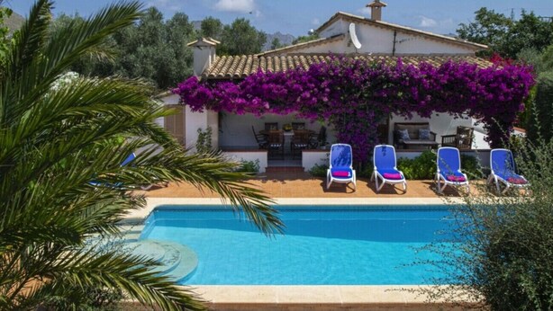 A villa with a swimming pool, a covered patio with lounge chairs, and a lush garden. - VILLA CAN TORRETA (Pollensa)