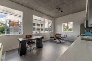 A modern kitchen with large windows, a dining area, and a concrete ceiling. - Brand New Spacious 1 bedroom in Wynwood (Miami)