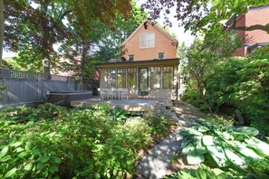 Ein Haus mit Terrasse, Ziegelaußenwand und einem Garten mit verschiedenen Pflanzen.