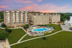 A multi-story hotel with a swimming pool and a landscaped lawn.