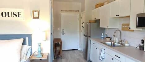 Une chambre d’hôtel moderne, équipée d’un lit, d’une table de chevet et offrant une vue sur la cuisine.