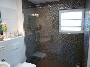 Ein Badezimmer mit Dusche, Waschbecken und Fenster.