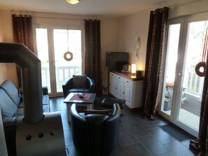 Ein Wohnzimmer mit einer Couch, einem Tisch, einem Fernseher und einem Kamin.