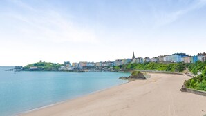 A coastal town with a sandy beach, a pier, and colorful buildings along the shoreline. - 4 Bed in Tenby (oc-a42730) (Tenby)