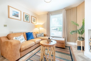 Ein Wohnzimmer mit einer Couch, einem runden Couchtisch, einer Lampe und einer Zimmerpflanze.