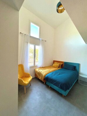 Ein Schlafzimmer mit Bett, Stuhl, Fenster und Deckenleuchte.