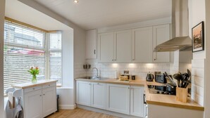 A modern kitchen with white cabinets, a wooden countertop, a built-in oven, and a window with blinds. - 3 Bed in Skipton (oc-h42831) (Skipton)