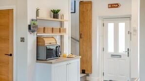 A kitchen with a microwave, wooden cabinets, and a sign indicating a pub direction. - 3 Bed in Skipton (oc-h42831) (Skipton)