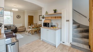 A modern kitchen with a dining area, a staircase, and a living room with a sofa and a coffee table. - 3 Bed in Skipton (oc-h42831) (Skipton)