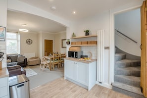 Eine moderne Küche mit Essbereich, einer Treppe und einem Wohnzimmer mit Sofa und Couchtisch.