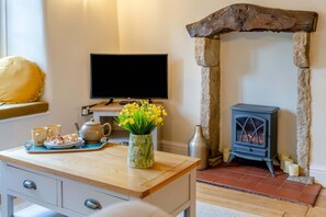 A cozy room with a wooden desk, a television, a stone fireplace, and a vase with flowers. - 2 Bed in Leyburn (oc-l42746) (Leyburn)