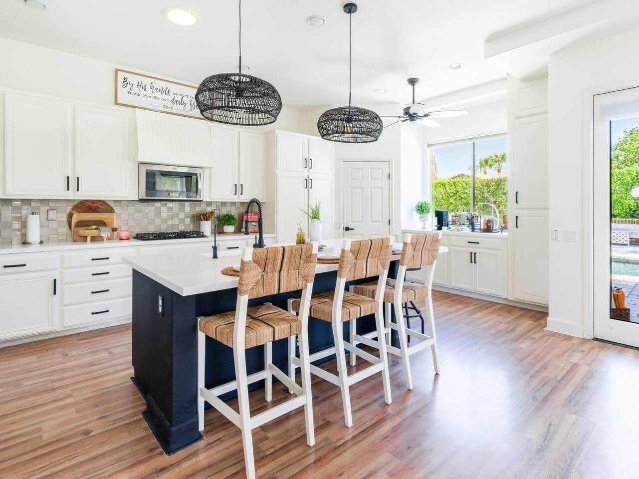 Una cocina moderna con armarios blancos, una isla central y taburetes de bar.