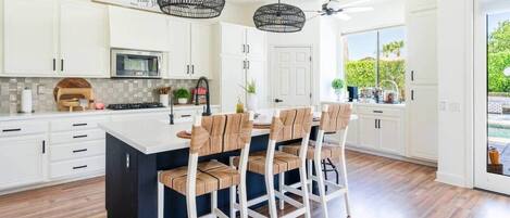 Una cocina moderna con armarios blancos, una isla central y taburetes de bar.
