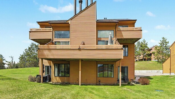 A modern two-story house with a flat roof, large windows, and a covered outdoor seating area. - Spacious 3 bdrm, 2 Bath Plus Loft, 1630 Sq Ft.  Many onsite amenities with Golf/Skiing near by! (Harbor Springs)