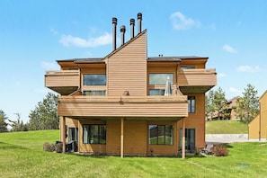 Una casa moderna de dos pisos con techo plano, amplios ventanales y una zona de estar exterior cubierta.