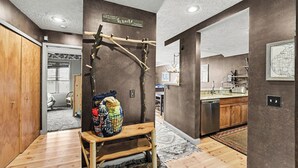 A modern kitchen with wooden cabinets, a stainless steel dishwasher, and a hanging wooden rack. - Spacious 3 bdrm, 2 Bath Plus Loft, 1630 Sq Ft.  Many onsite amenities with Golf/Skiing near by! (Harbor Springs)