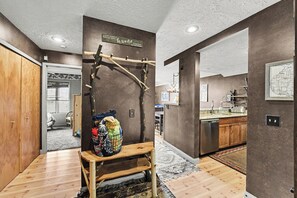 A modern kitchen with wooden cabinets, a stainless steel dishwasher, and a hanging wooden rack. - Spacious 3 bdrm, 2 Bath Plus Loft, 1630 Sq Ft.  Many onsite amenities with Golf/Skiing near by! (Harbor Springs)