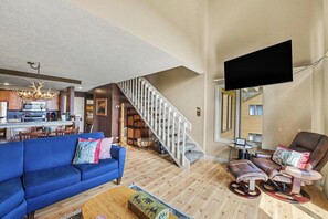 A living room with a blue sofa, a recliner, a wooden coffee table, a staircase, and a kitchen in the background. - Spacious 3 bdrm, 2 Bath Plus Loft, 1630 Sq Ft.  Many onsite amenities with Golf/Skiing near by! (Harbor Springs)