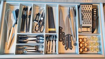 Un tiroir contenant divers ustensiles et outils de cuisine, rangés dans des compartiments.