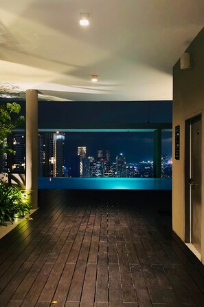 A balcony with a city view at night, wooden flooring, and a door on the right.