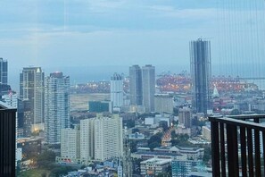 A cityscape with high-rise buildings, a mix of residential and commercial structures, and a distant view of a body of water. - 53rd floor TriZen 1BR Apartment - Stunning Views (Colombo)