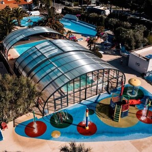 A swimming pool with a glass enclosure, water play area, and palm trees. - Beach 1km, 4/6 pers, St Georges - ile d'Oléron (Saint-Georges-d'Oléron)