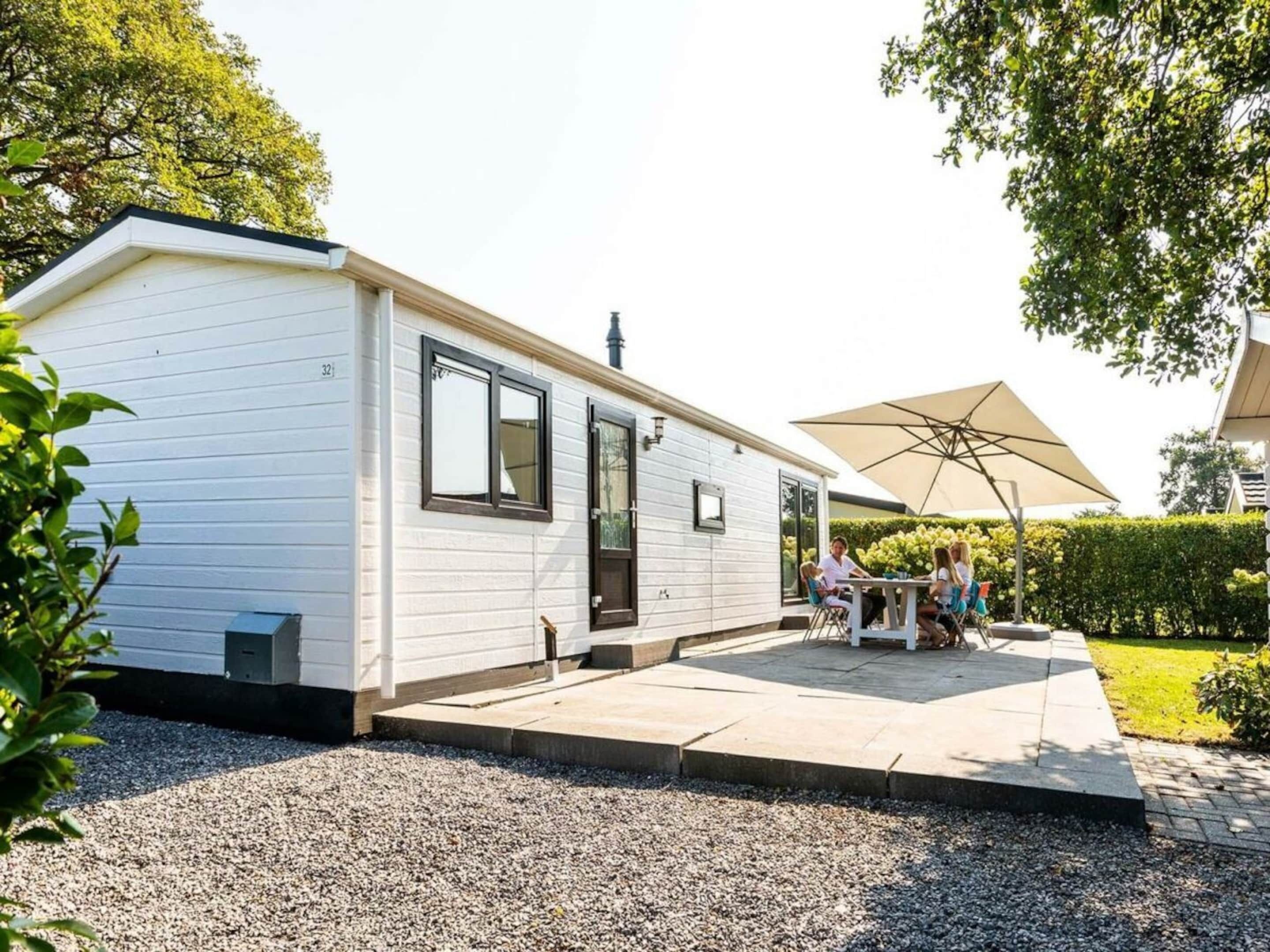 A mobile home with a patio area, a table with chairs, and an umbrella.