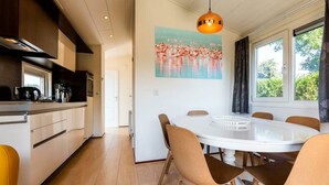 Eine moderne Küche mit Essbereich, Holzboden und einem großen Fenster mit Vorhängen.