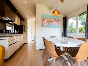 Eine moderne Küche mit Essbereich, Holzboden und einem großen Fenster mit Vorhängen.