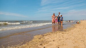 Eine Strandansicht, wie eine Familie am Ufer entlangspaziert.