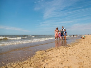 Eine Strandansicht, wie eine Familie am Ufer entlangspaziert.