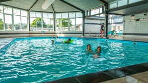 Ein überdachter Innenpool mit klarem Wasser und gefliestem Boden.