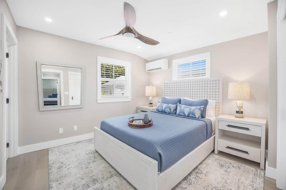 A bedroom with a bed, nightstands, a ceiling fan, and a window with blinds.