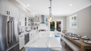 Uma cozinha moderna com ilha central, eletrodomésticos de aço inoxidável e um espaço de refeições com bancos.