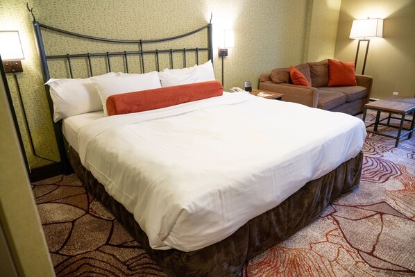 Une chambre d’hôtel avec un lit, un canapé, une table de chevet et une lampe.