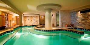 A swimming pool with a circular design, a stone wall, and a glass door leading to a shower area. - Mountain Lodge Room | Steps to Downtown Banff (Banff)